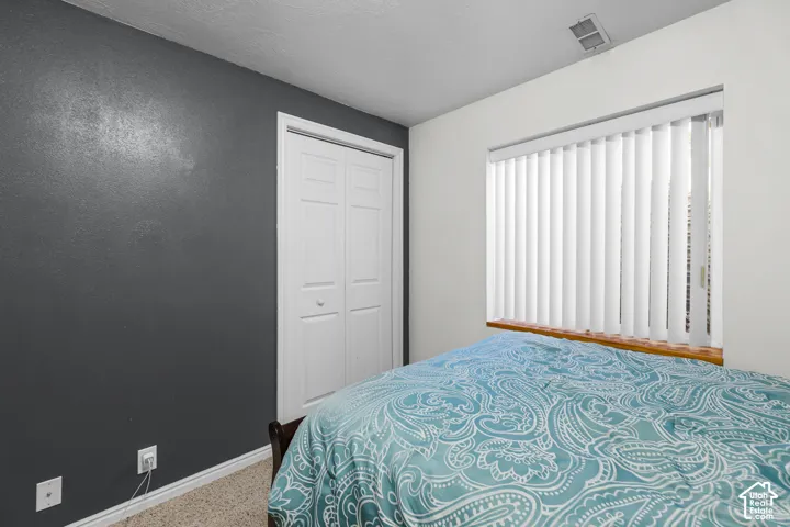 Vertical blinds on a window with a wood sill, textured accent wall, and bi-fold closet doors