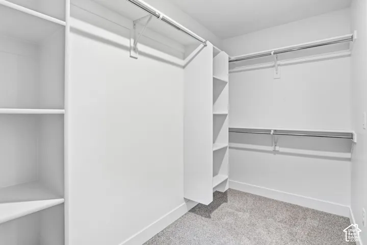 White shelving units with integrated storage rods, multiple hanging rods, and carpet flooring