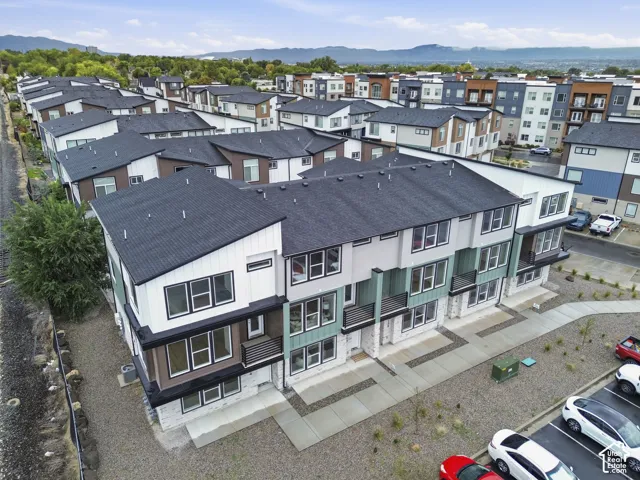 Contemporary townhome design with a multi-level exterior, dark asphalt shingle roofing, and contrasting light-colored siding