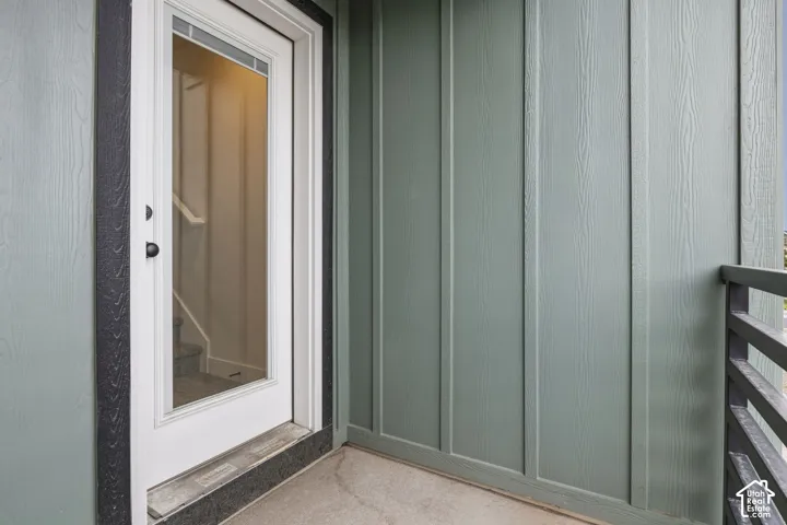 Patio area featuring vertical panel siding, a full-lite exterior door with a transom, and a black metal railing
