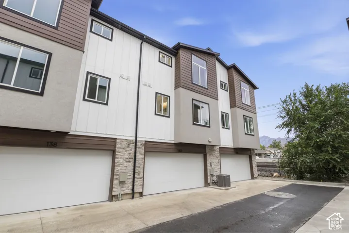 Multi-level townhome exterior featuring contemporary siding, stone veneer accents, and multiple windows
