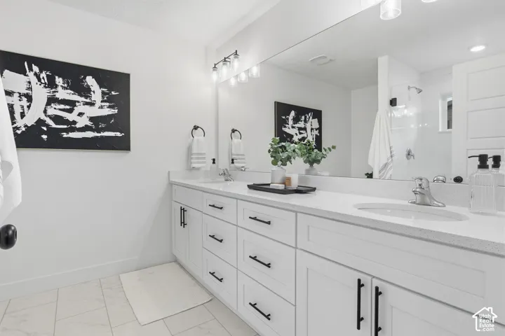 Dual vanity with white shaker cabinetry, polished chrome fixtures, and a large integrated mirror