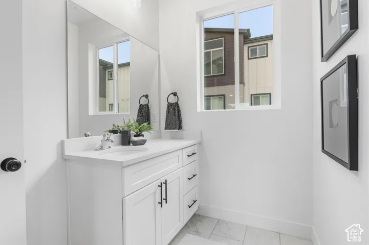 White vanity with dark hardware, quartz countertop, and undermount sink