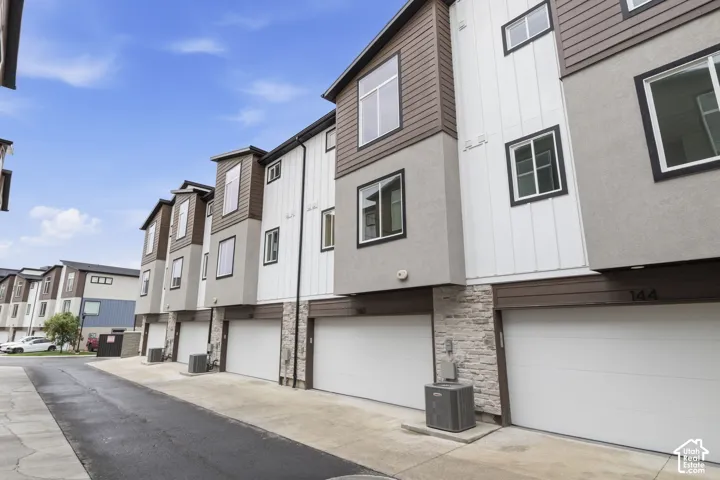 Contemporary townhome exterior with mixed-material siding, large windows, and an attached garage