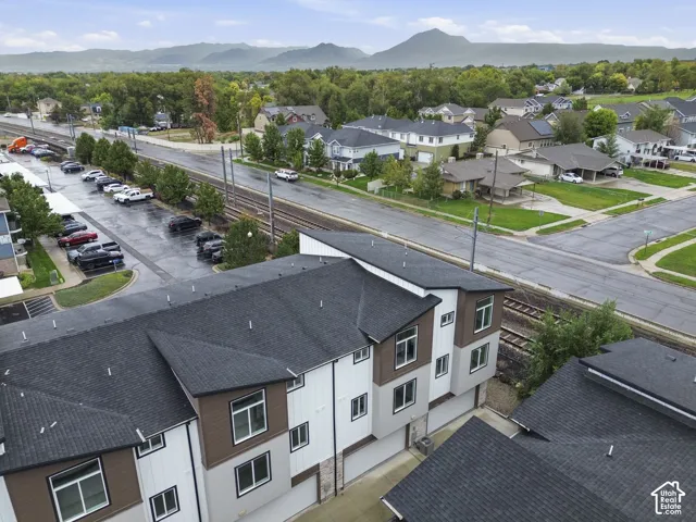Newly constructed multi-story townhomes with white and brown siding, dark shingle roofing, and attached garages