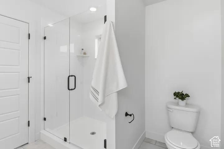 Glass-enclosed shower with a matte black handle and wall-mounted shower head