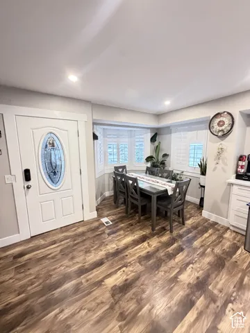 Wood-finish flooring throughout, white paneled door with leaded glass insert, bay window with plantation shutters, recessed lighting, and white cabinetry