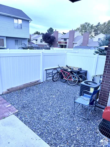 Gravel outdoor space featuring a privacy fence, brick exterior wall, and concrete patio section