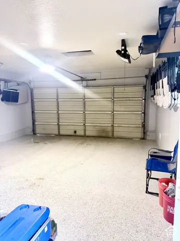 Garage space featuring a speckled epoxy floor, white walls, and a sectional garage door