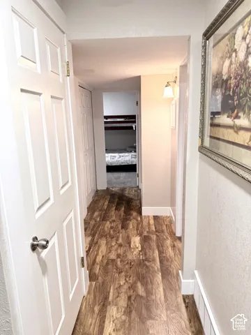 Wood-finish flooring throughout, white paneled doors, and wall-mounted sconce lighting