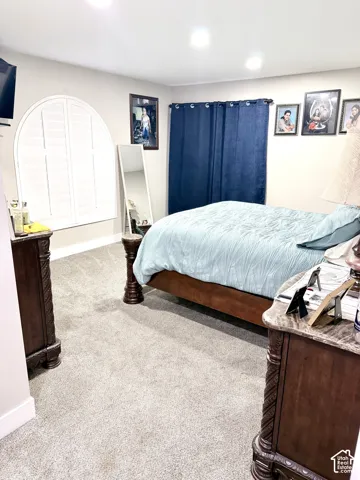 Arched window with plantation shutters, recessed lighting, and soft carpeting