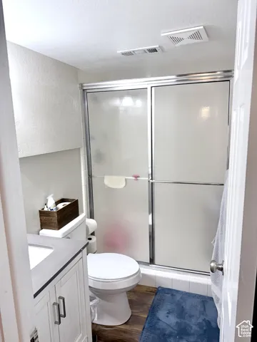 Compact bathroom featuring a white vanity with brushed nickel hardware, a gray countertop, and wood-finish flooring