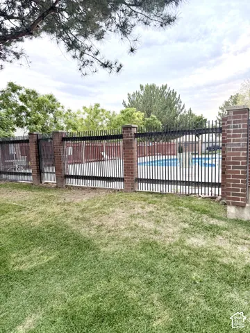 Private swimming pool enclosed by a brick and wrought iron fence
