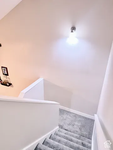 Carpeted stairs with white risers and a white painted half-wall