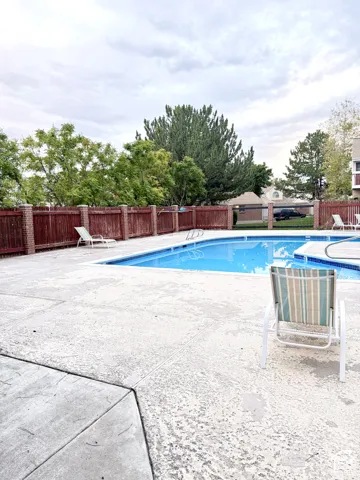 Outdoor swimming pool with a textured concrete deck and perimeter fencing