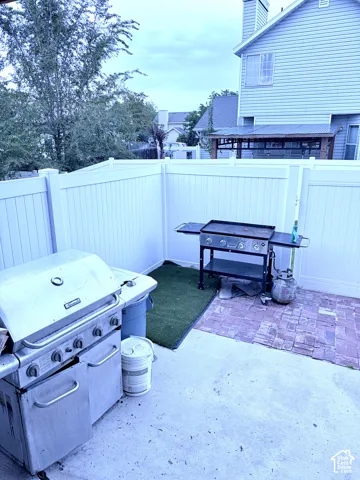 Private patio space with white privacy fencing, concrete flooring, and a brick paver area