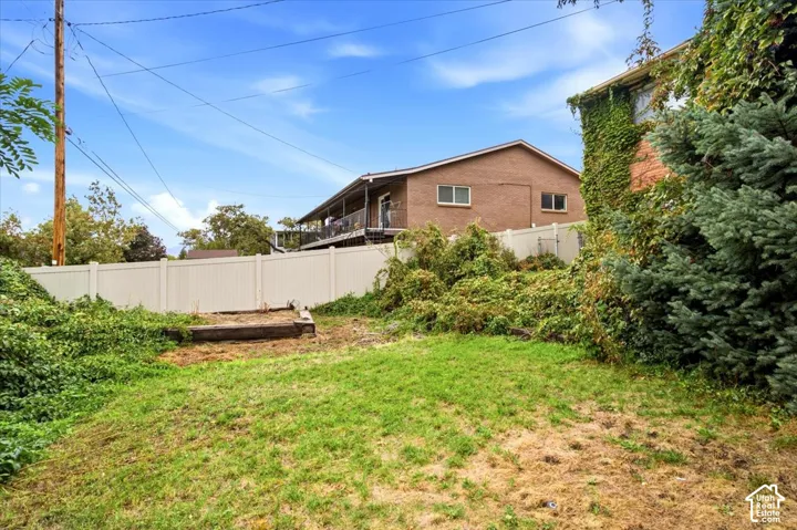 Expansive outdoor space featuring a white privacy fence and established plantings