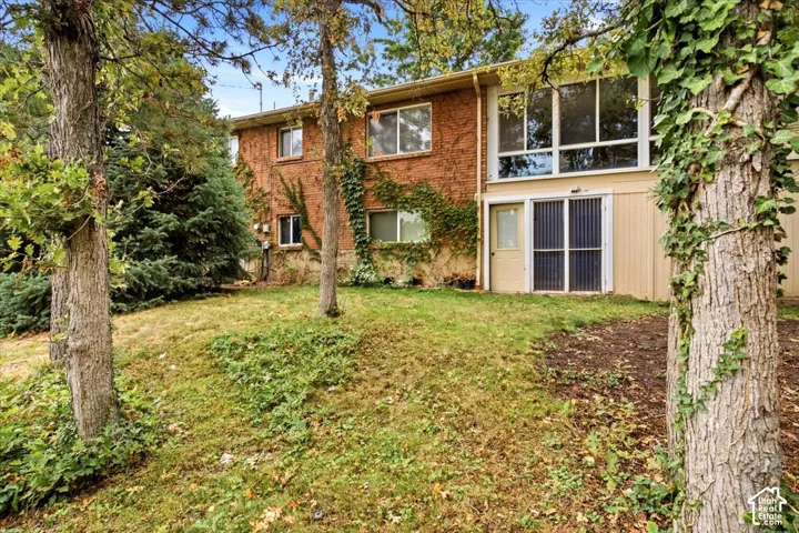 Brick exterior with multiple windows, large ground-level windows, and a sliding glass door