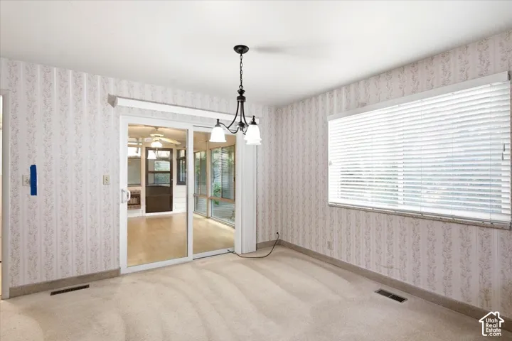 Sliding glass door, large window with blinds, overhead lighting fixture, and patterned wallpaper