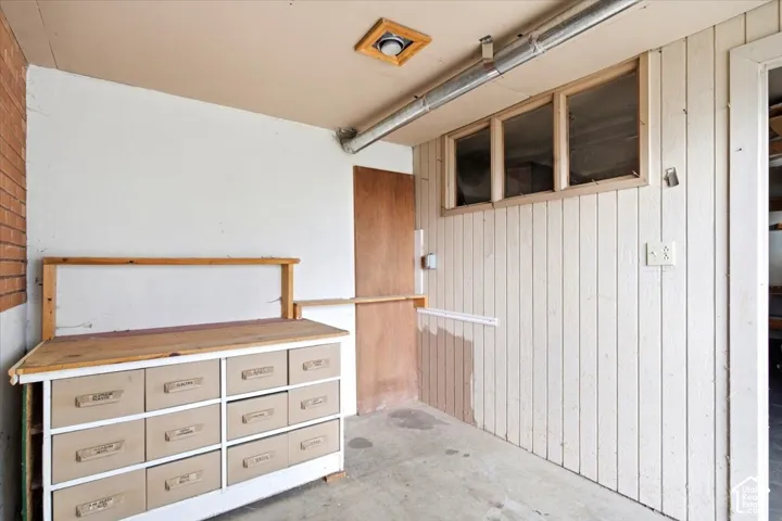 Vertical paneling on walls, exposed brick wall, concrete flooring, wooden-framed windows