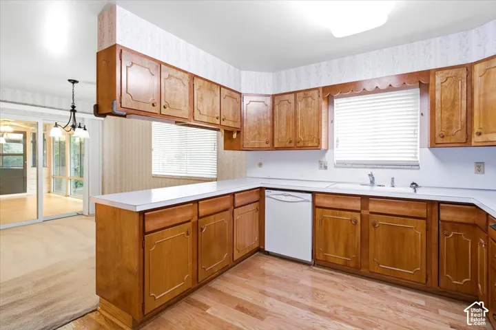 Kitchen featuring wood cabinetry, white countertops, a built-in dishwasher, and wood-finish flooring
