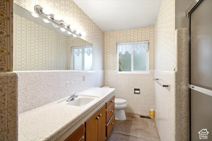 Bathroom featuring a built-in vanity with integrated sink, full-width mirror, overhead bar lighting, and a sliding glass shower enclosure