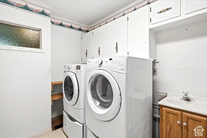 Laundry area featuring upper cabinetry, a utility sink with a wood-finish vanity, and a textured glass window