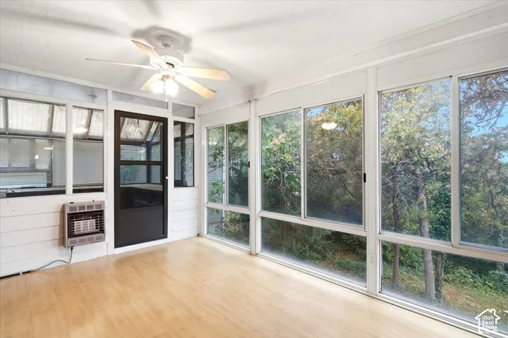 Sunroom featuring wood-finish flooring, ceiling fan, and extensive window panels