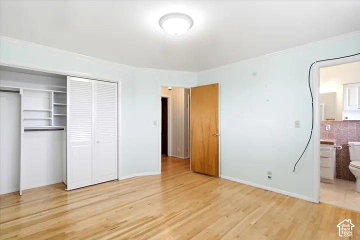 Hardwood flooring, white crown molding, recessed lighting, bi-fold closet doors, and built-in closet shelving