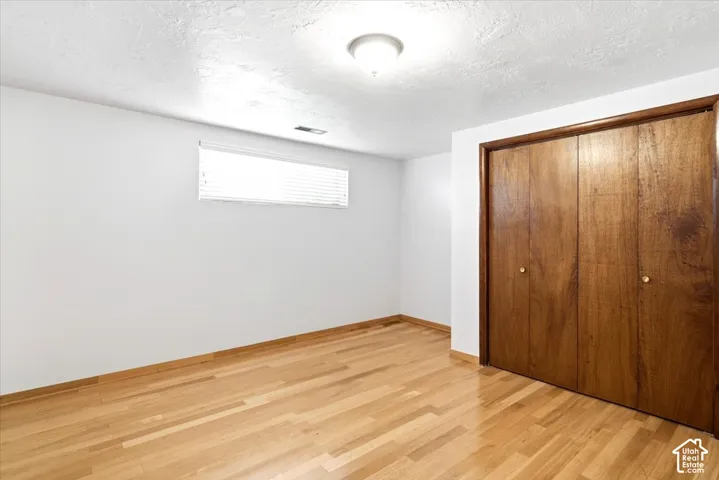 Hardwood flooring, recessed window with blinds, and wood-finish bifold closet doors