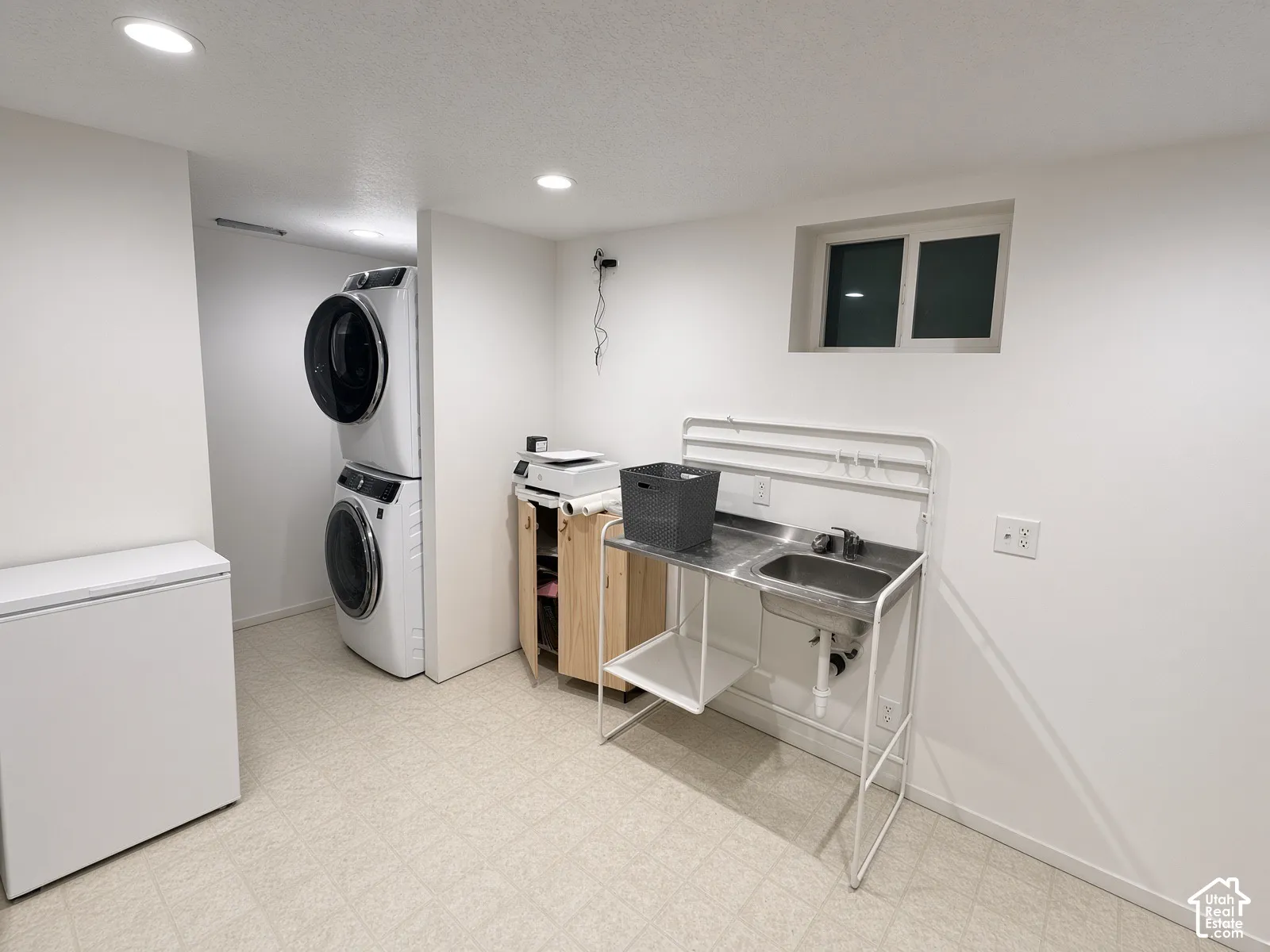 Recessed lighting, painted white walls, vinyl flooring, and a utility sink