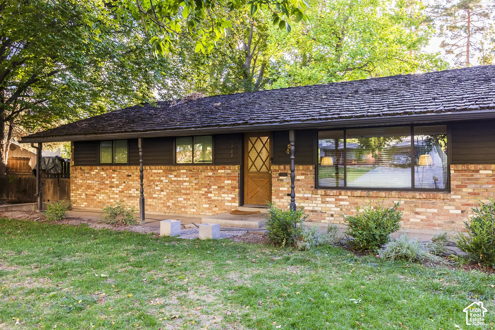 Brick and wood-sided exterior featuring a prominent picture window and shingle roof