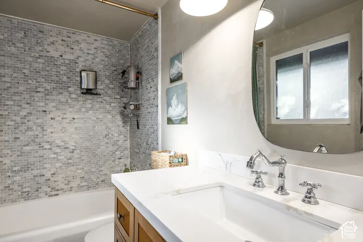 Bathroom featuring a white bathtub, subway tile surround, polished chrome fixtures, white countertop, and wood-finish vanity
