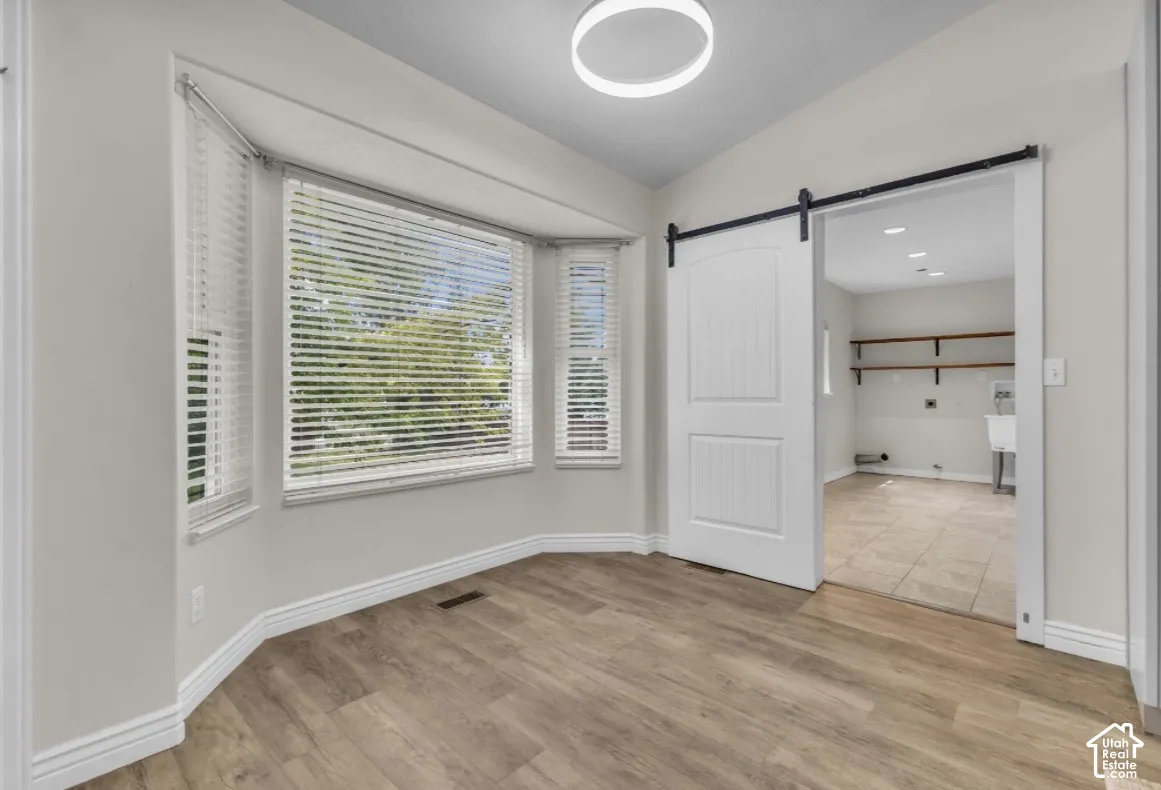 Wood-finish flooring, bay window, modern ceiling light fixture, barn door, and tiled flooring