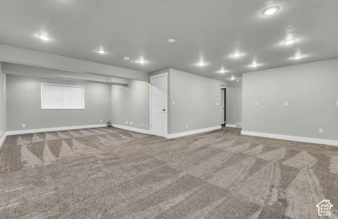 Generous room featuring recessed lighting, a window with blinds, and durable carpeting
