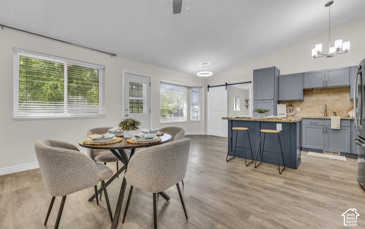 Open concept living space featuring wood-finish flooring, vaulted ceilings, and a kitchen island with seating