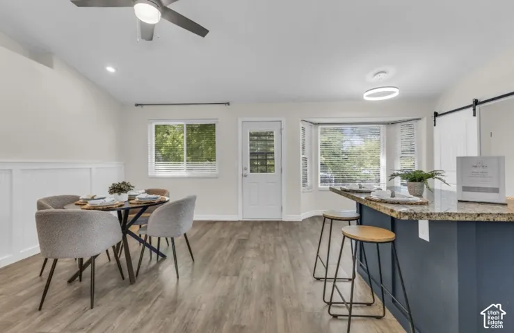 Wood-finish flooring, wainscoting detail, recessed lighting, ceiling fan, and bay window