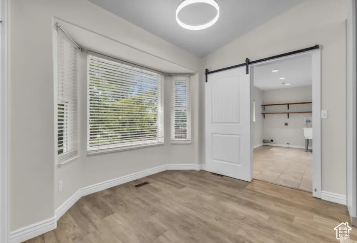 Wood-finish flooring, bay window, modern ceiling light fixture, barn door, and tiled flooring