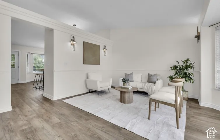 Wood-finish flooring throughout, white wall paneling, and contemporary wall sconces illuminate the space
