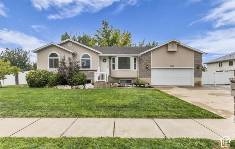 Stucco and brick exterior with arched windows, a two-car garage, and a manicured lawn