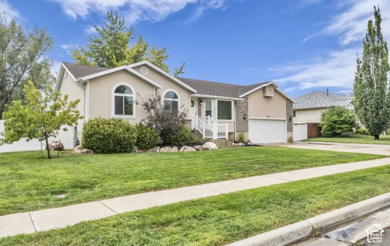 Stucco and brick exterior with arched windows, attached garage, and a concrete sidewalk