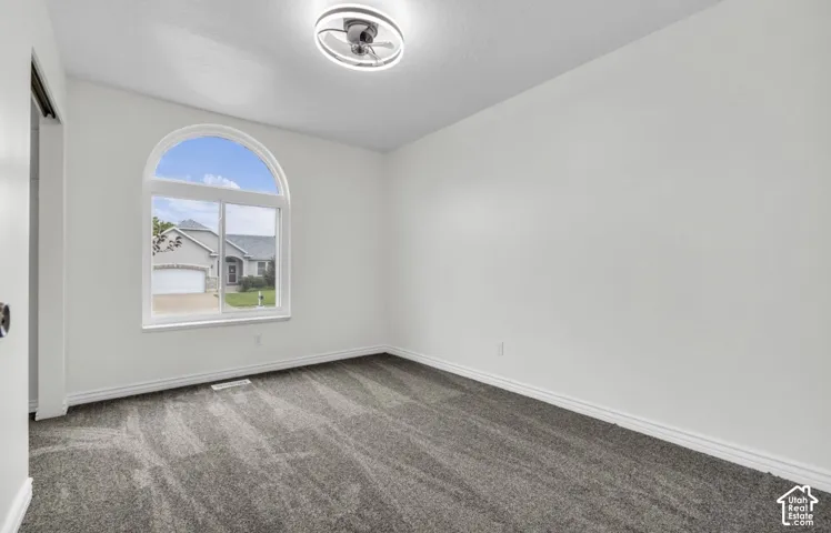 Arched window, gray carpet, white walls, white trim, and a modern ceiling light fixture