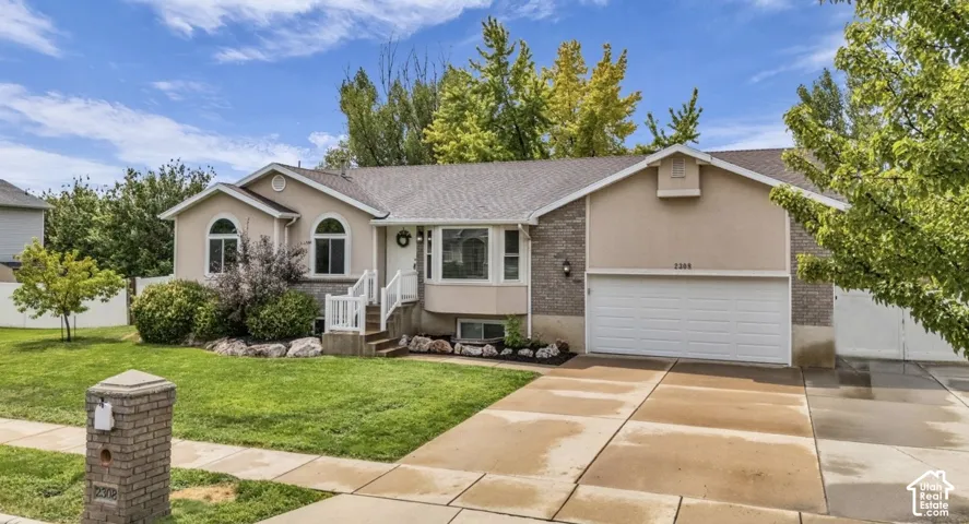 Exterior featuring a two-car garage, stucco and stone-finish siding, arched windows, and a concrete driveway