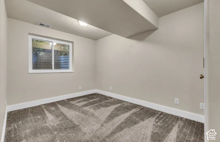 Neutral wall color, window, patterned carpet, flush mount ceiling lighting, and white trim