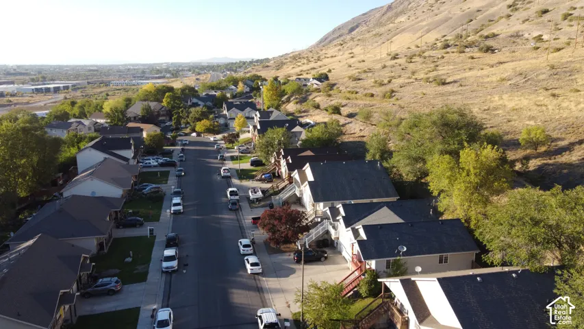 Aerial perspective of a neighborhood featuring hillside topography, mature trees, and residential street infrastructure