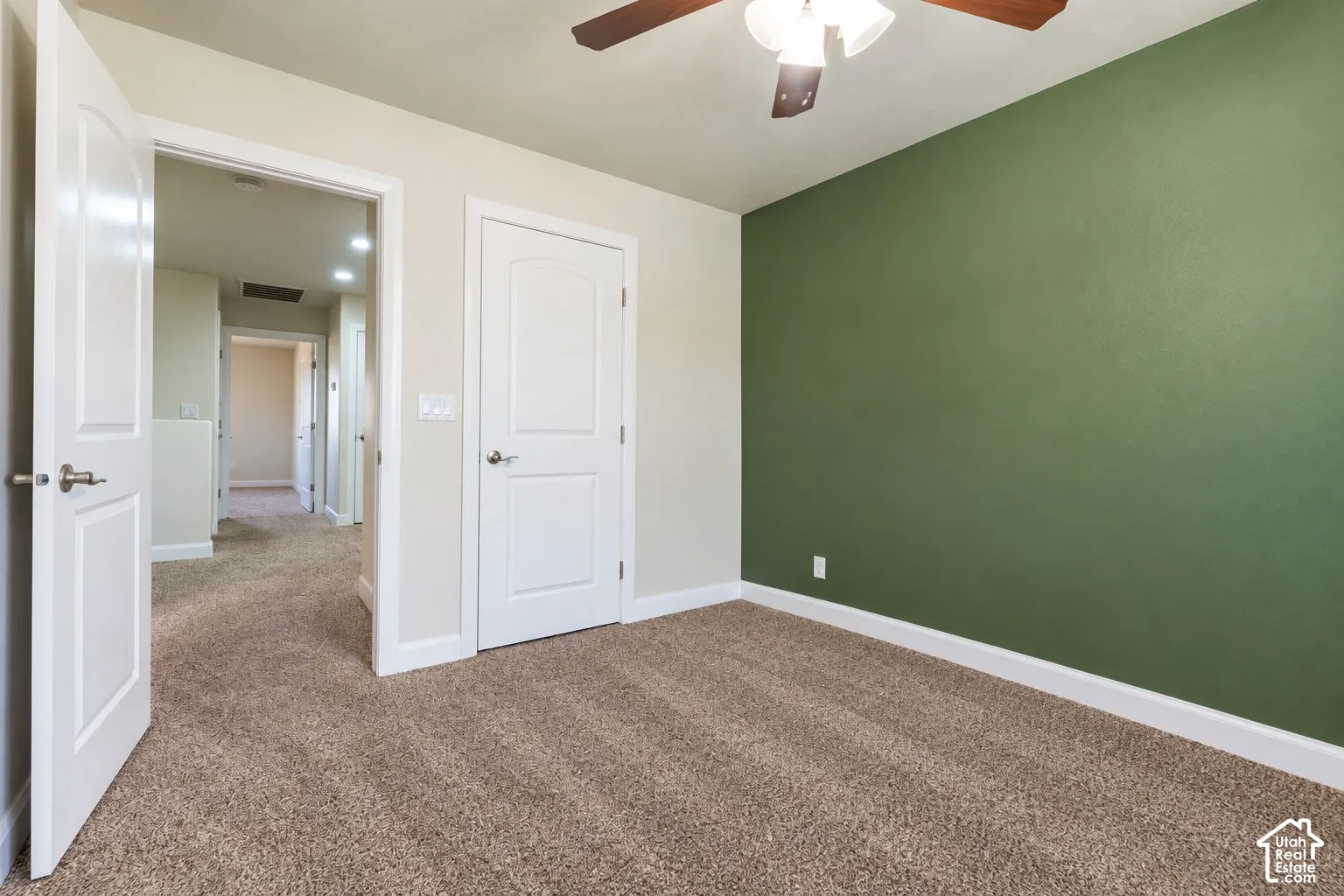 Carpeted flooring, ceiling fan with integrated lighting, a dedicated accent wall, and white panel doors