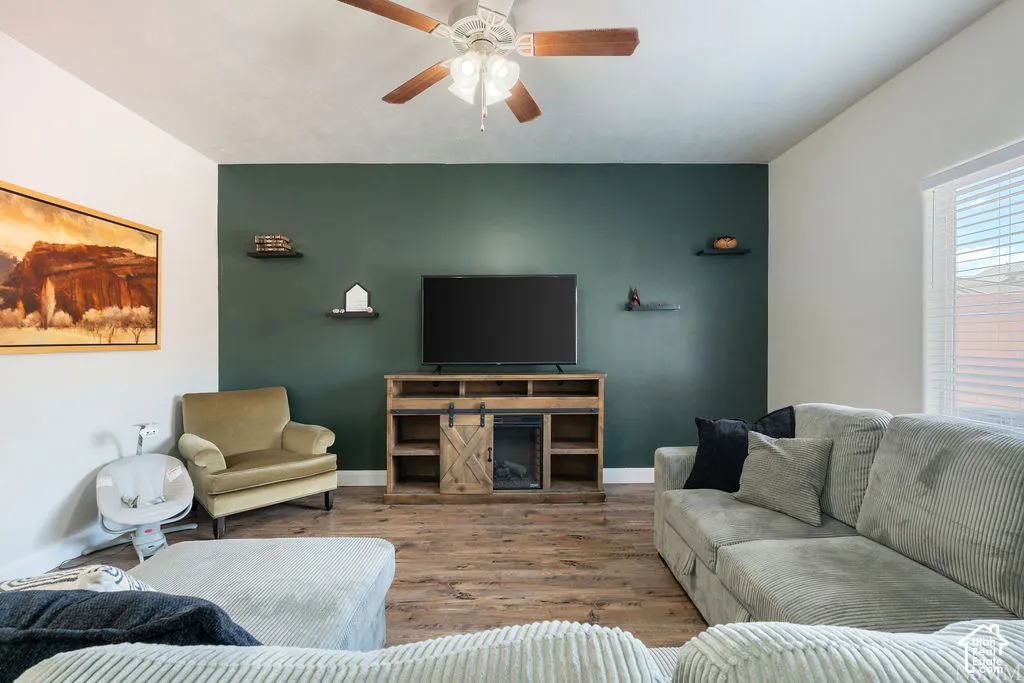 Wood-finish flooring with a contrasting accent wall, ceiling fan, and built-in window blinds