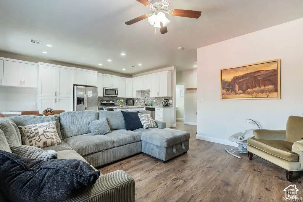 Open-concept living area featuring wood-finish flooring, recessed lighting, and a ceiling fan
