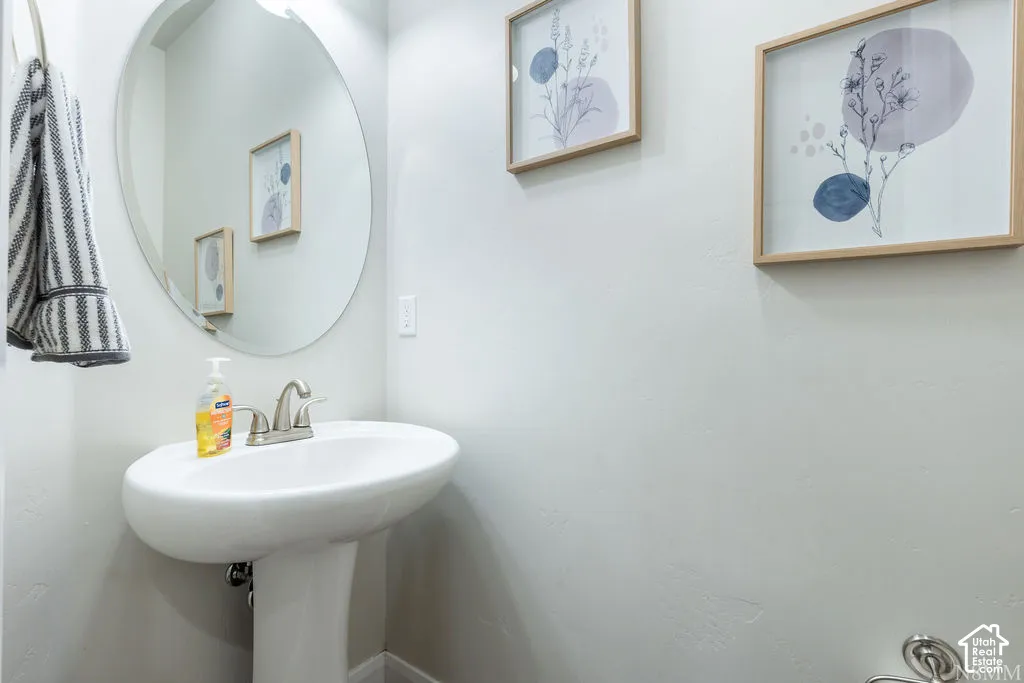 White pedestal sink with a brushed nickel faucet and a circular mirror