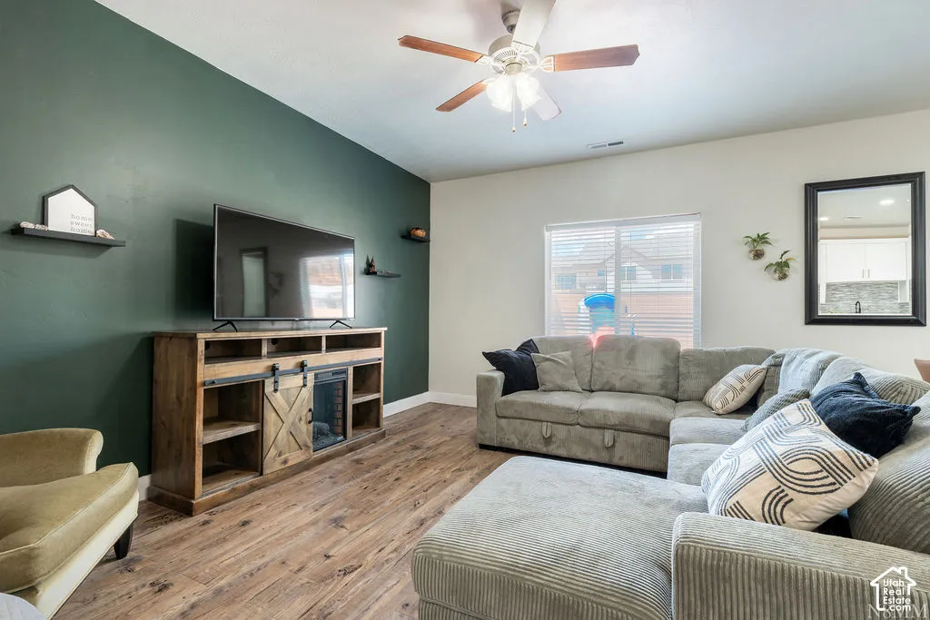 Wood-finish flooring, accent wall, ceiling fan, built-in shelving, window with blinds